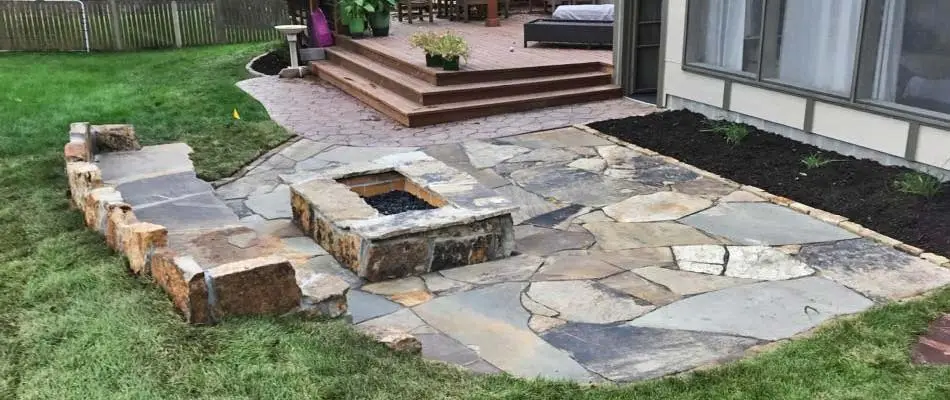 Custom square flagstone fire pit with a flagstone patio and seating wall at a home in Lancaster County.