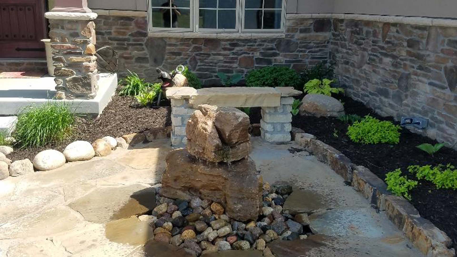 Landscaping installed in front of a home in Lincoln with a water feature as a focus.
